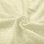 Pościel frotte 200x220 w kolorze kremowym, zbliżenie na miękką, teksturowaną powierzchnię materiału, ułożoną w naturalnych falach, podkreślającą jego grubość i jakość. Tło jednolite, co uwydatnia produkt.