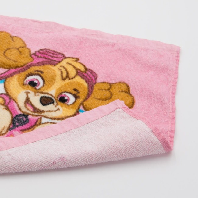 Ręcznik dziecięcy 30x30 cm w kolorze różowym, z wizerunkiem Skye z Psi Patrol. Wykonany z bawełny, z miękką fakturą. Ułożony na białym tle, widoczny brzeg i zagięty róg. Brzeg wykończony jasnoróżowym obszyciem.