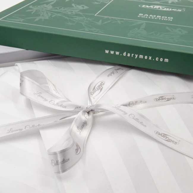 Pościel bambusowa satynowa 160x200 w białe paski, zapakowana w zielone opakowanie z logo DARYmex. W widoku z góry, widoczna satynowa tkanina oraz biała wstążka zdobiona napisem Luxury Collection. Opakowanie ma elegancki, prosty design.