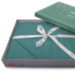 Pościel bambusowa satyna bawełniana 160x200 w kolorze turkusowym, zapakowana w eleganckie pudełko z motywem bambusa. W zestawie znajduje się miękka narzuta w paski, z ozdobną kokardą z białej wstążki. Opakowanie otwarte, pokazujące zawartość.