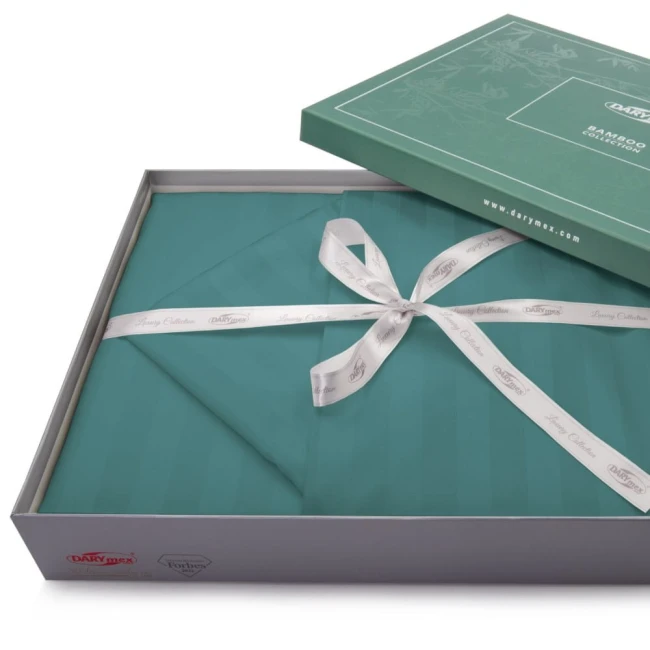 Pościel bambusowa satyna bawełniana 160x200 w kolorze turkusowym, zapakowana w eleganckie pudełko z motywem bambusa. W zestawie znajduje się miękka narzuta w paski, z ozdobną kokardą z białej wstążki. Opakowanie otwarte, pokazujące zawartość.