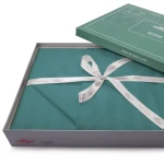 Pościel bambusowa satyna bawełniana w kolorze turkusowym, z paskami, rozmiar 220x200. Produkt leżący w otwartej, ozdobnej pudełku, z widoczną wstążką. Opakowanie z logo DARYmex, wykonane z kartonu, z delikatnym wzorem roślinnym na wieczku.