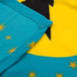 Kocyk dziecięcy 100x150 cm w odcieniu błękitnym z żółtym wzorem. Widoczne są stylizowane gwiazdki w różnych kolorach. Produkt leży płasko, pokazując detale szwów i tekstury materiału. Miękka, polarowa faktura.