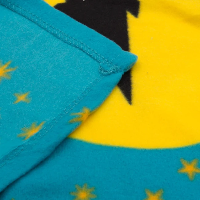 Kocyk dziecięcy 100x150 cm w odcieniu błękitnym z żółtym wzorem. Widoczne są stylizowane gwiazdki w różnych kolorach. Produkt leży płasko, pokazując detale szwów i tekstury materiału. Miękka, polarowa faktura.
