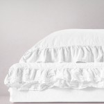 Pościel bawełniana z falbanką 160x200 w kolorze optic white, leżąca na płaskiej powierzchni. Poduszka z falbanką i gładkim wykończeniem, pokazująca delikatną strukturę materiału. Tło w neutralnym odcieniu, co podkreśla jasność produktu.