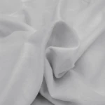 Flanelowe prześcieradło bez gumki w jasnym szarym kolorze, wykonane z teksturowanego materiału. Złożone, w widoku z góry, ukazuje miękkość i delikatność tkaniny, surowy, elegancki akcent do aranżacji wnętrza.