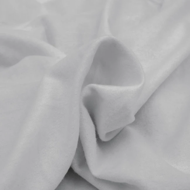 Flanelowe prześcieradło bez gumki w jasnym szarym kolorze, wykonane z teksturowanego materiału. Złożone, w widoku z góry, ukazuje miękkość i delikatność tkaniny, surowy, elegancki akcent do aranżacji wnętrza.