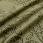 Pościel bawełniana 220x200 w kolorze zielonym z delikatnym czarnym wzorem liści. Ułożona na płasko, z widoczną teksturą materiału. Zdjęcie zbliżone, uwydatniające detale wzoru i faktury tkaniny.