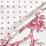 Pościel satyna bawełniana 220x200 Luxury Rose Blanc w kolorze białym z czerwonymi kropkami oraz wzorem kwiatowym. Obiekt leży na płaskiej powierzchni, z widocznym zamkiem błyskawicznym w poszewce. Tekstura materiału jest gładka.