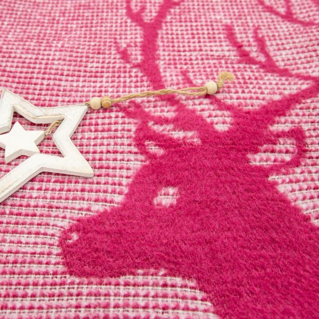 Koc bawełniany 150x200 cm w bordowym kolorze, z wzorem renifera. Produkt leży na płaskiej powierzchni, ujęcie w zbliżeniu. Widoczna tekstura materiału, dekoracyjna gwiazda w białym kolorze obok koca. Tło w harmoni z wzorem, nadające świąteczny charakter.