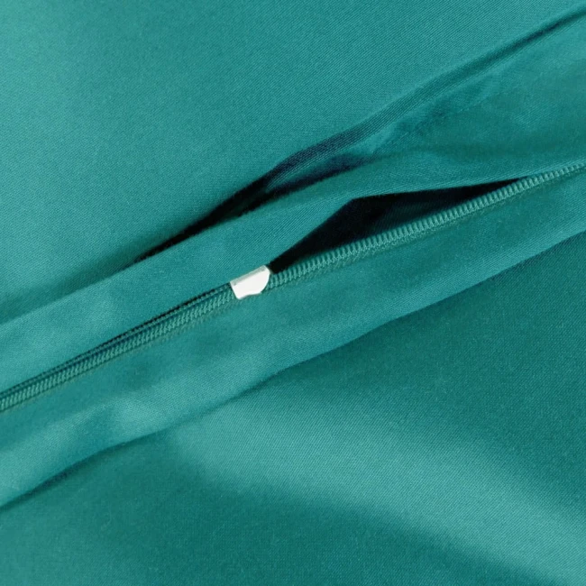 Pościel satyna bawełniana 180x200 w kolorze ciemnego turkusu, z widocznym zamkiem błyskawicznym. Ułożona na gładkim tle, detale tkaniny podkreślają teksturę materiału. Produkt leży, z odsłoniętą częścią na zamek, co ułatwia wgląd w zamknięcie.
