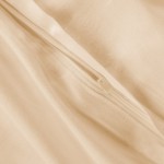 Pościel satyna bawełniana 180x200 w kolorze jasnego beżu, widok z bliska na zamek błyskawiczny oraz gładką fakturę materiału. Produkt leży na płaskiej powierzchni, ukazując detale szycia i wykończeń.