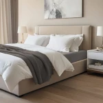 Prześcieradło jersey z elastanem w kolorze antracyt, rozmiar 160x200, leżące na materacu. Widoczna faktura materiału, gładkie wykończenie. W otoczeniu jasne poduszki i narzuta w odcieniach bieli, minimalistyczne wnętrze sypialni.