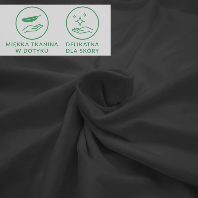Prześcieradło jersey z elastanem w kolorze czarnym, gładkie, leżące w eleganckim ułożeniu. W tle znajdują się ikony informujące o miękkiej tkaninie i delikatności dla skóry. Produkt idealny do łóżka o wymiarach 180x200 cm.