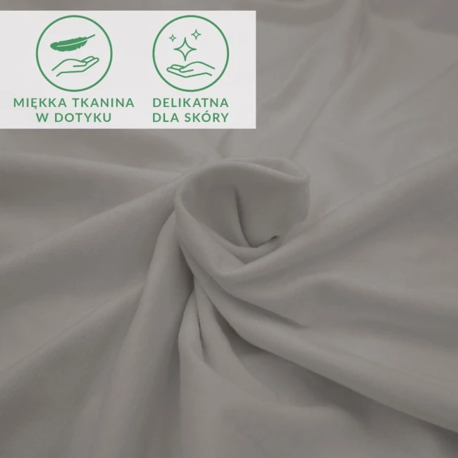 Prześcieradło jersey z elastanem w kolorze popielatym, z gumką. Zbliżenie na materiał, ukazujące gładką, elastyczną tkaninę, o delikatnej strukturze, zwinięte w dekoracyjnym układzie. Widoczne ikony informujące o miękkości i delikatności dla skóry.