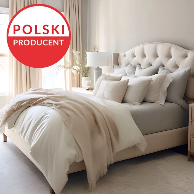 Prześcieradło jersey z elastanem z gumką 180x200 w kolorze popiel szaro-beżowym, leżące na łóżku z jasnym obiciem. Widoczne złożone poduszki i narzuta, z delikatnym materiałem. Tło jasne, z naturalnym światłem wpadającym przez okna.