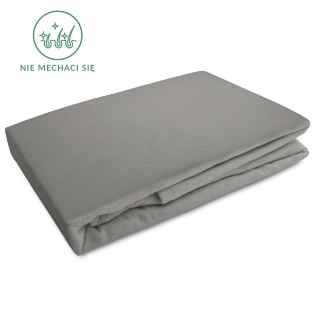 Flanelowe prześcieradło z gumką w kolorze szarym, o wymiarach 200x220 cm, leży na płasko. Widać gładką, lekko teksturowaną powierzchnię materiału. W prawym górnym rogu widoczny znaczek Nie mechaci się. Tło proste i jednolite.