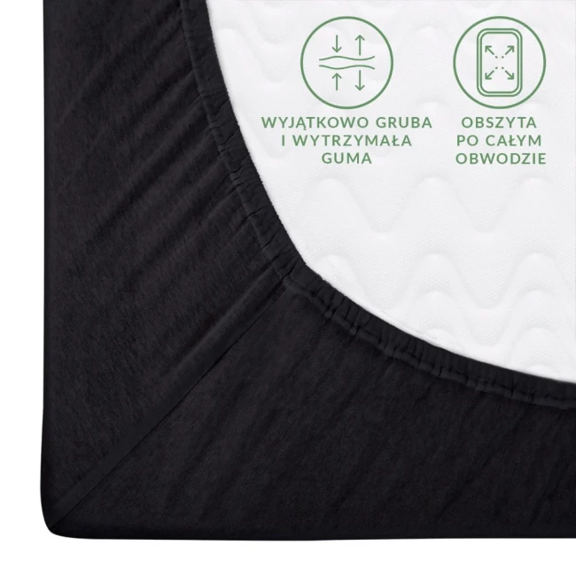 Prześcieradło jersey z gumką w kolorze czarnym, z widoczną gumą w obwodzie. Zbliżenie na kąt produktu, ukazujące grubość i elastyczność tkaniny, z białym wnętrzem. Obok napisy informacyjne o cechach użytkowych.