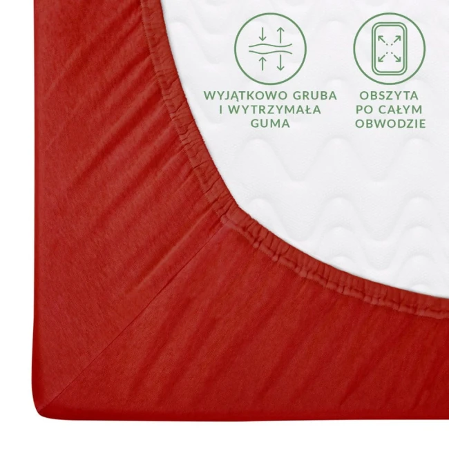 Prześcieradło jersey z gumką 140x200 w kolorze czerwonym, leżące na białym tle. Ujęcie z boku, pokazujące szczegóły obramowania. Widoczna gruba, elastyczna guma oraz tekst informacyjny o właściwościach materiału.