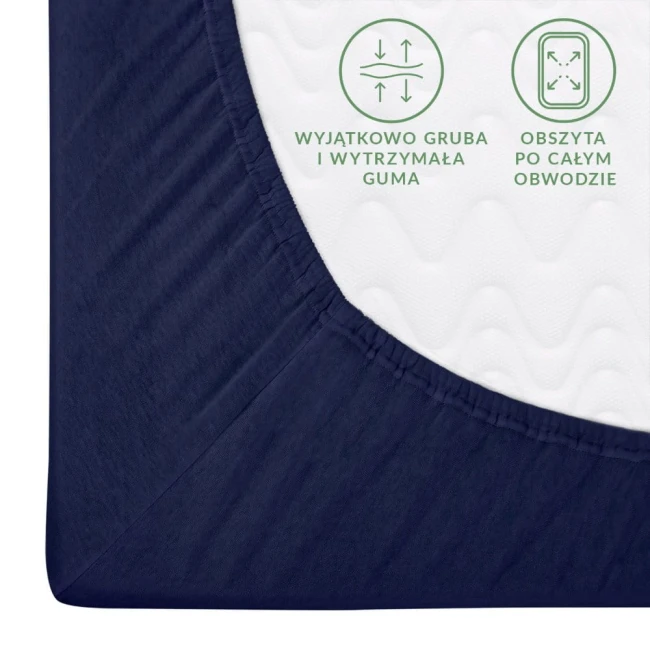 Prześcieradło jersey z gumką 180x200 w kolorze ciemnego granatu, widok z boku, rozłożone na powierzchni. Z gładką, elastyczną fakturą, obszyte przez cały obwód, z widocznymi detalami opisującymi gumo-wytrzymałość. Tło jednolite.