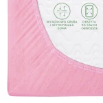 Prześcieradło jersey z gumką 60x120 w jasnoróżowym kolorze, rozłożone na białym tle. Widoczna elastyczna guma, obszyta na całym obwodzie. Zbliżenie na fakturę tkaniny oraz grafiki z opisem wytrzymałości materiału.