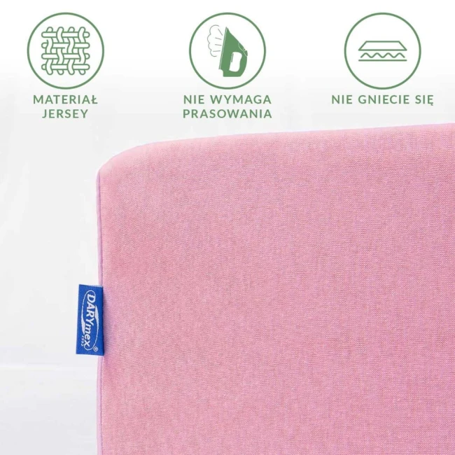 Prześcieradło jersey z gumką 140x200 w jasnoróżowym kolorze, leżące na białym tle. Widoczny detal materiału oraz mała metka w niebieskiej etykietce. Produkt nie wymaga prasowania i nie gniecie się.