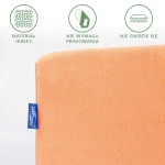 Prześcieradło jersey z gumką w kolorze łososiowym, złożone, widoczne logo w niebieskiej etykiecie. Materiał nie wymaga prasowania i nie gniecie się, co podkreślają grafiki obok. Tło proste, białe.