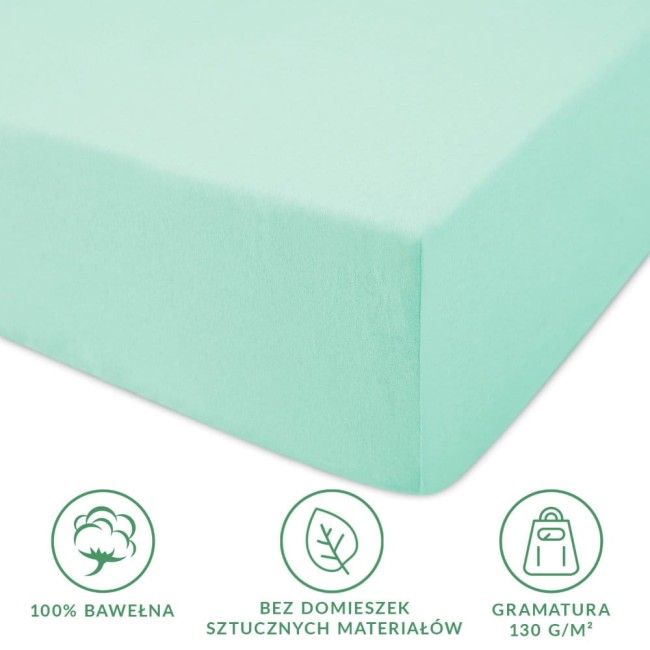 Prześcieradło jersey z gumką 160x200 w kolorze morskim, wykonane z 100% bawełny. Złożone, widok z boku, ukazuje gładką teksturę oraz jasny kolor. Na zdjęciu widoczne ikonki informujące o materiale i gramaturze (130 g/m²). Tło jednolite.
