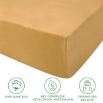 Prześcieradło jersey z gumką w kolorze musztardowym, leżące na białym tle. Wykonane z 100% bawełny, z gramaturą 130 g/m². Widoczne logo oraz informacje o braku sztucznych materiałów. Kształt dostosowany do materaca 140x200 cm.