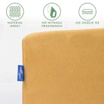 Prześcieradło jersey z gumką w kolorze musztardowym, leżące na białym tle. Zbliżenie na fakturę materiału, z widoczną metką w niebieskim kolorze. Wskazania dotyczące braku potrzeby prasowania oraz odporności na gniecenie.