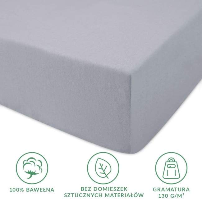 Prześcieradło jersey z gumką w kolorze popielatym 160x200 cm, leżące na gładkiej powierzchni. Wykonane z 100% bawełny, o gramaturze 130 g/m², z widocznymi informacjami o składzie i właściwościach materiału. Brak sztucznych domieszek.