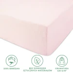Różowe prześcieradło jersey z gumką 140x200, wykonane w 100% z bawełny, bez sztucznych domieszek. Widok z boku, ukazuje gładką, delikatną fakturę tkaniny. Opis na dole informuje o gramaturze 130 g/m².