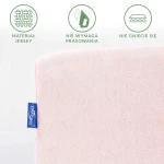 Prześcieradło jersey z gumką 120x200 w kolorze różu kwarcowego, widoczne w zbliżeniu, z lewej strony widoczna niebieska metka z logo. Materiał gładki, nie wymaga prasowania i nie gniecie się, podkreślony kontekst graficzny z informacjami.