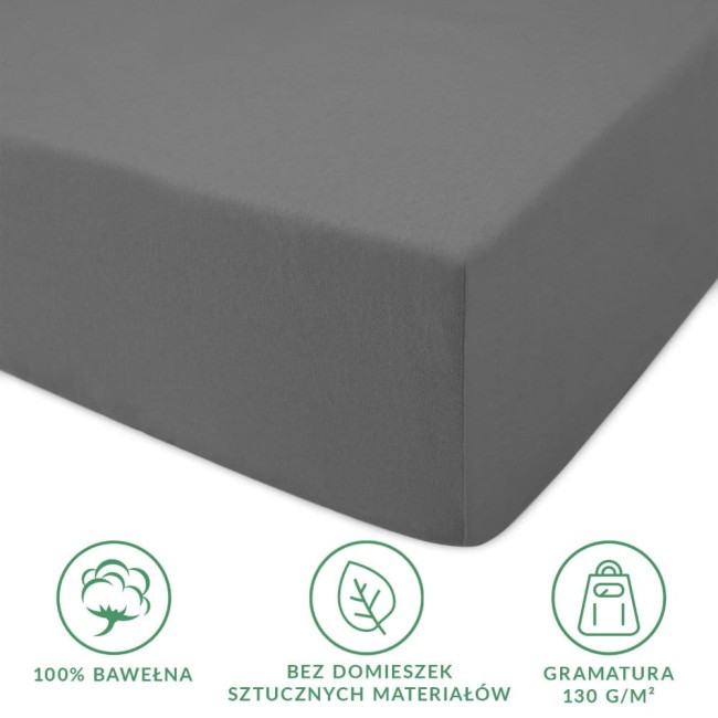 Prześcieradło jersey z gumką 90x200 w kolorze szarym, wykonane z 100% bawełny, na zdjęciu pokazane z boku, leżące na płaskiej powierzchni. Widoczne są wyraźne napisy informujące o składzie oraz gramaturze 130 g/m².
