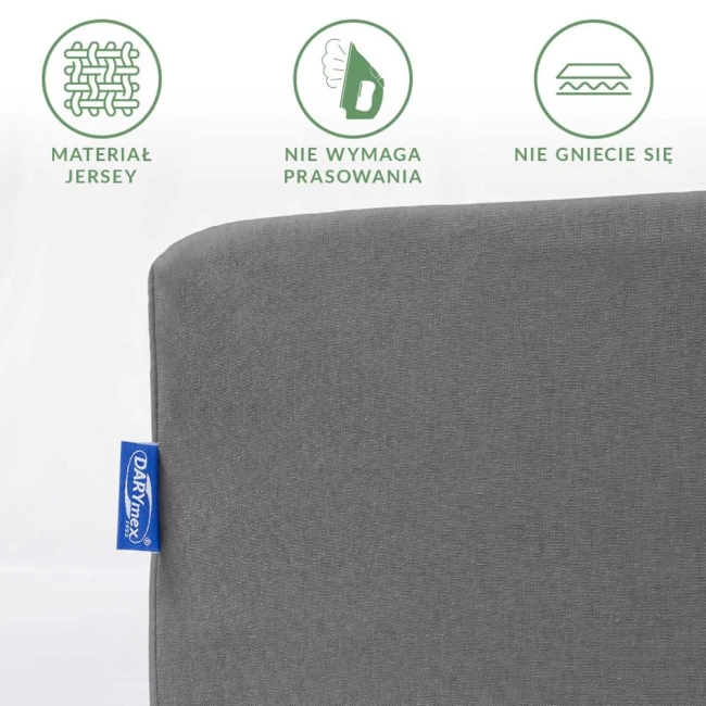 Prześcieradło jersey z gumką w kolorze szarym, w leżącej pozycji, z widocznym detalem tkaniny. Z boku widoczna metka z logo DARYMEX. Tło proste, białe. Produkt nie wymaga prasowania i nie gniecie się. Wymiary 90x200.