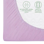 Prześcieradło jersey z gumką w kolorze wrzosowym, rozmiar 120x200. Widoczne jest połączenie elastycznej gumy z teksturą materiału. Na brzegach umieszczone są czytelne napisy informujące o trwałości gumy i obsztykaniu obwodu. Ujęcie z boku, na jasnym tle.