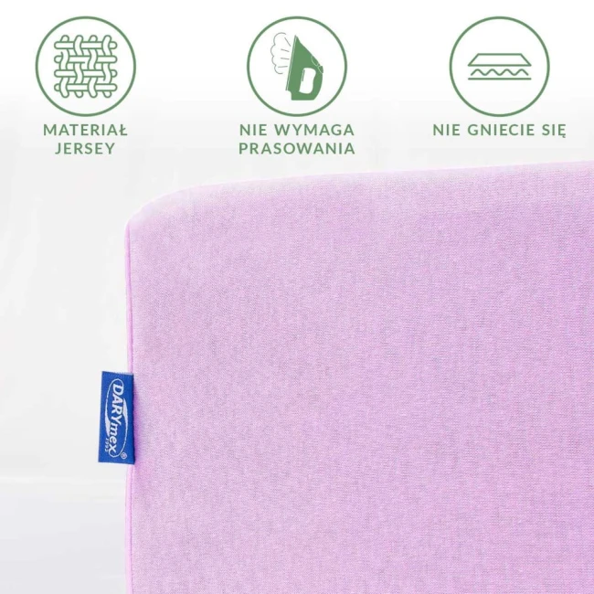 Prześcieradło jersey z gumką 120x200 w kolorze wrzosowym, leży na białym tle. Widoczne logo na niebieskiej etykiecie. Materiał gładki, nie wymaga prasowania, elastyczny. Ujęcie z boku, ukazujące krawędzie i fakturę tkaniny.