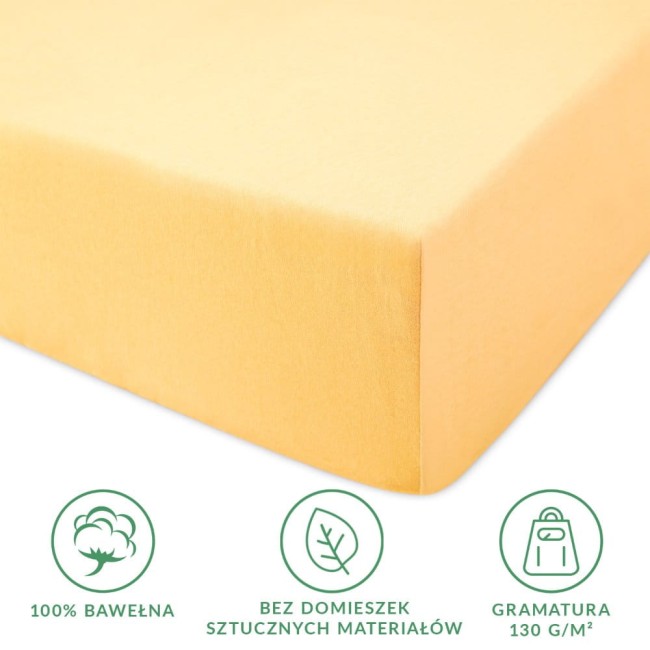 Prześcieradło jersey z gumką w kolorze żółtym, wykonane w 100% z bawełny, leżące na białym tle. Widoczny jest narożnik prześcieradła ze gumką, zapewniającą dopasowanie do materaca.