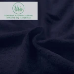 Prześcieradło frotte z gumką w ciemnym granacie, wykonane z miękkiego materiału o teksturowanej powierzchni. Ujęcie z bliska ukazuje falujący materiał, podkreślając jego elastyczność. Na tle widoczny napis informacyjny o odporności na przecieranie.