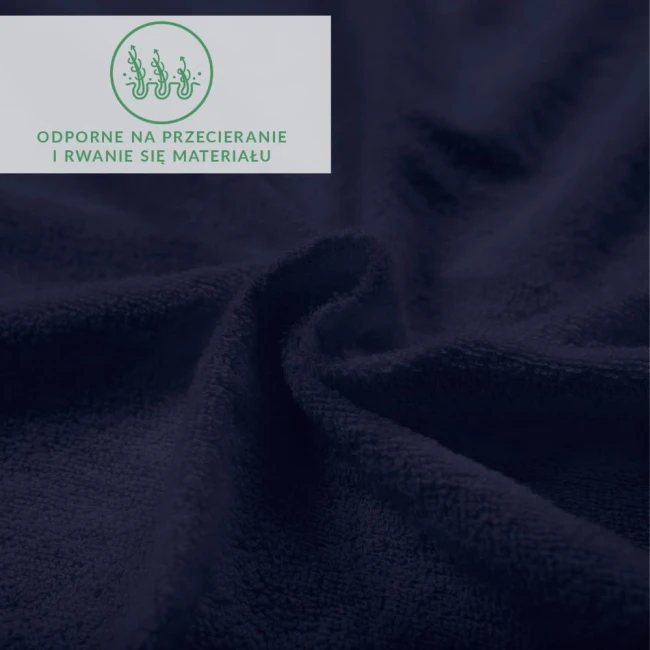 Prześcieradło frotte z gumką w ciemnym granacie, wykonane z miękkiego materiału o teksturowanej powierzchni. Ujęcie z bliska ukazuje falujący materiał, podkreślając jego elastyczność. Na tle widoczny napis informacyjny o odporności na przecieranie.