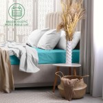 Prześcieradło frotte z gumką 120x200 w kolorze turkusowym leży na łóżku. Widoczna jest miękka struktura materiału oraz nałożona jasnoszara pościel i poduszki. W tle roślinność w wazonie oraz stół nocny z koszem. Neutralne tło.