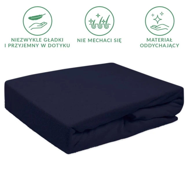 Prześcieradło frotte z gumką 140x200 w kolorze ciemnym granacie, leżące na gładkiej powierzchni. Widoczna tekstura materiału, prezentującego właściwości oddychające. Produkt posiada gumkę, co zapewnia lepsze dopasowanie do materaca.