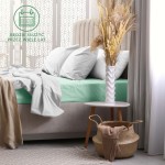 Prześcieradło frotte z gumką 160x200 w kolorze morskim, rozłożone na łóżku z poduszkami, leżące na jasnoszarym materacu. W tle widoczna elegancka dekoracja okna oraz minimalistyczny stolik z białym wazonem i suszonymi kwiatami.