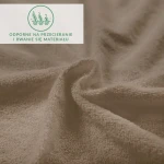 Prześcieradło frotte w kolorze kakao, rozłożone, z widoczną, teksturowaną powierzchnią. Tło w jednolitym odcieniu podkreśla materiał, a przezroczyste logo z informacją o odporności na przetarcia.