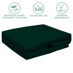 Prześcieradło frotte z gumką w kolorze zieleni butelkowej, leżące na płaskiej powierzchni. Materiał jest gładki i elastyczny, idealnie dopasowany do materaca. Prosty, ciemny odcień podkreśla nowoczesny design. Brak widocznych napisów lub logo.