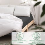 Prześcieradło satynowe z gumką 140x200 w kolorze czarnym, rozłożone na łóżku. Widoczne białe poduszki oraz jasna pościel podkreślają jego elegancki wygląd.