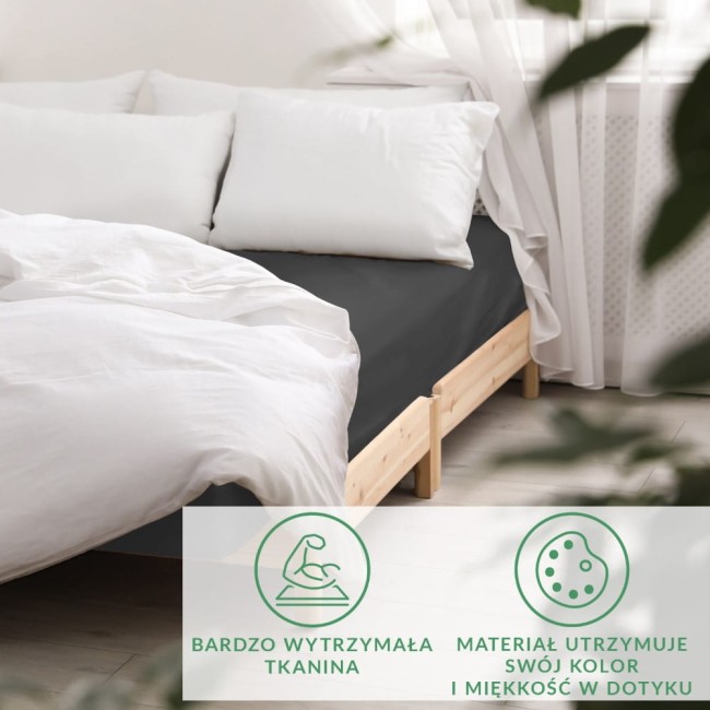 Prześcieradło satynowe z gumką 140x200 w kolorze czarnym, rozłożone na łóżku. Widoczne białe poduszki oraz jasna pościel podkreślają jego elegancki wygląd.