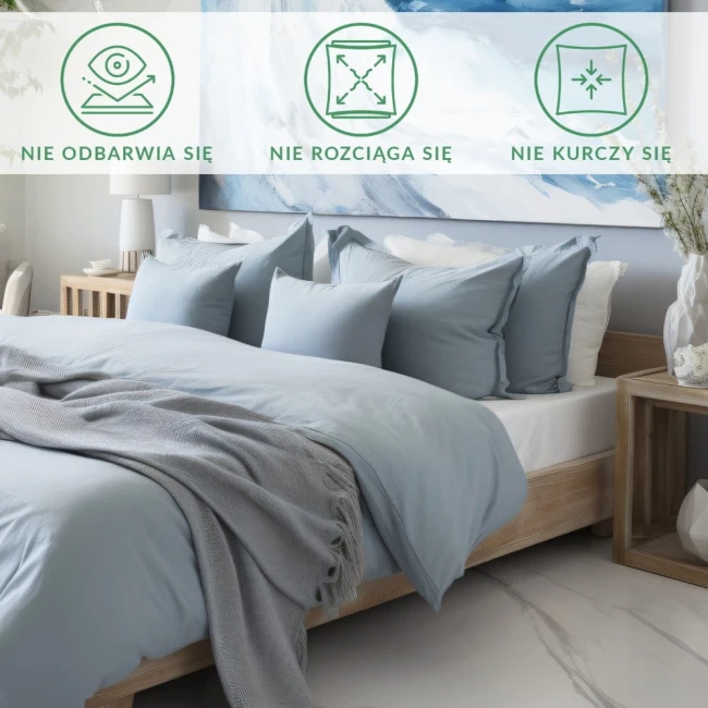 Prześcieradło satynowe 200x220 w kolorze kremowym, rozłożone na łóżku, otoczone poduszkami w różnych rozmiarach i szaro-białym kocem. Tło jasne, minimalistyczne z dekoracjami. Nie odbija światła, nie rozciąga się, nie kurczy.