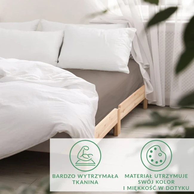 Prześcieradło satynowe z gumką w kolorze sepia, rozmiar 200x220, leży na łóżku z białą pościelą. W tle widoczne jaśniejsze poduszki oraz drewniana rama łóżka. Tkanina jest gładka i błyszcząca, wkomponowana w stonowaną aranżację wnętrza.