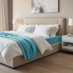 Prześcieradło jersey z elastanem w kolorze niebieskim, o wymiarach 90x200 cm, naciągnięte na materac. Widoczne na łóżku z białą pościelą i błękitnym kocem, w nowoczesnej sypialni z jasnym tłem.